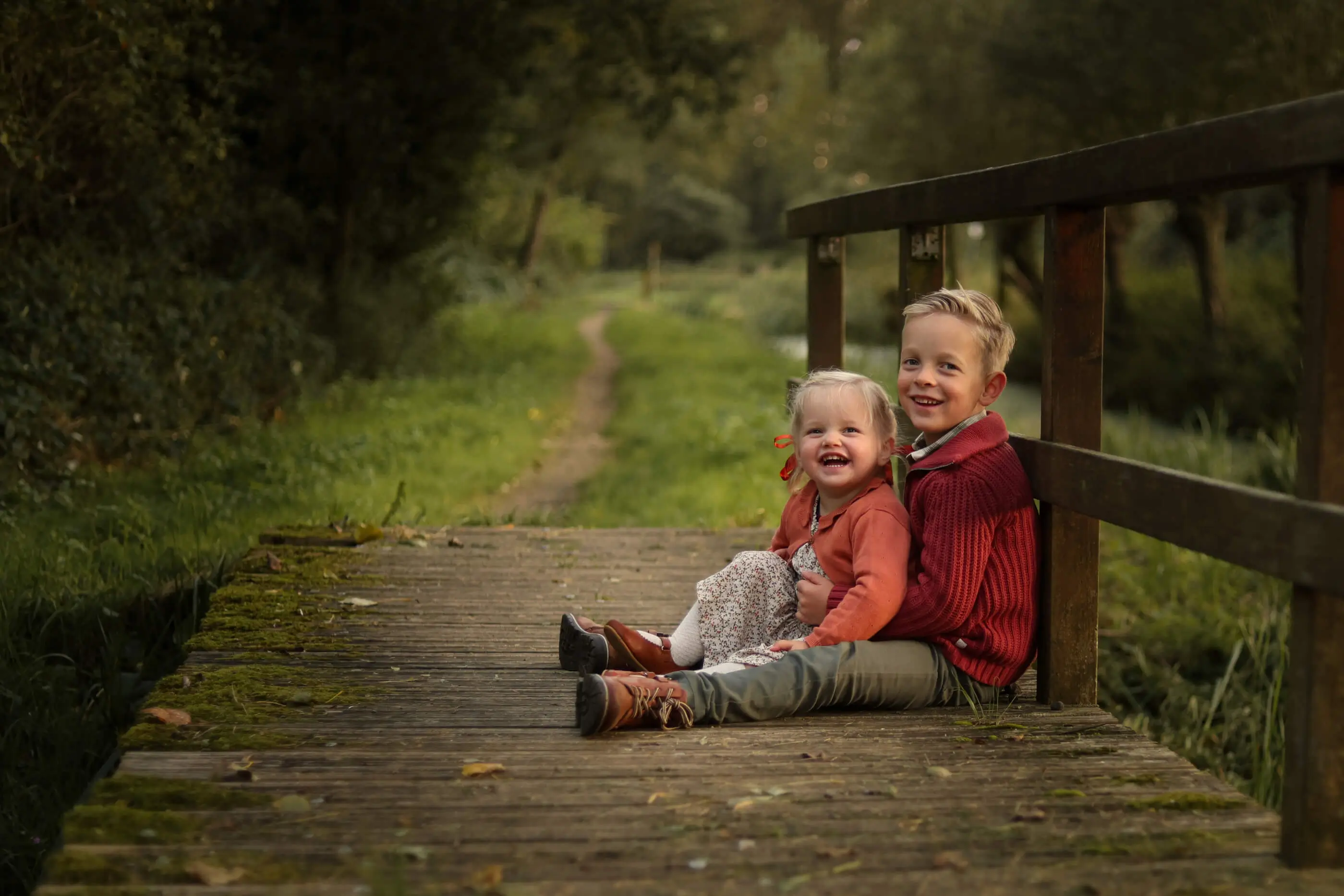 Twee kinderen samen op een houten bruggetje in het bos