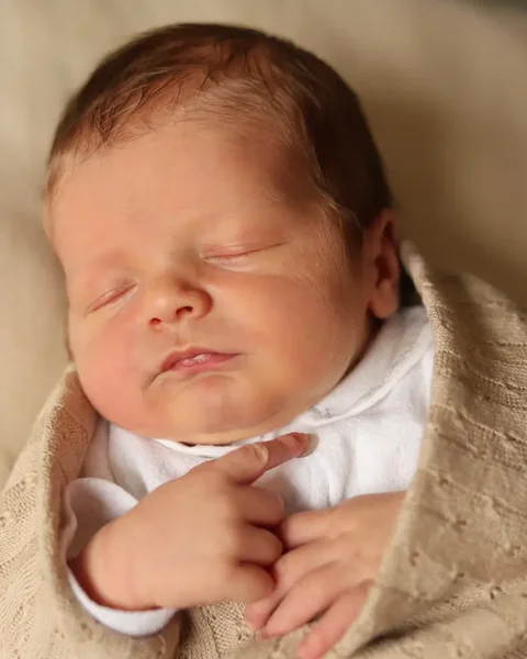 Slapende newborn in een zachte omslagdoek